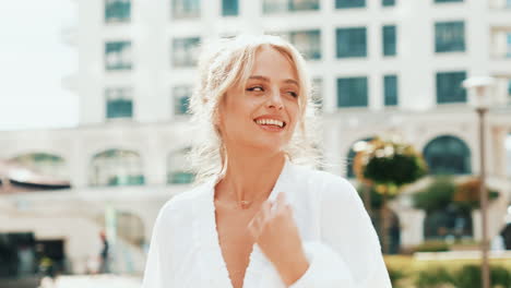 woman in a white robe smiling in the city