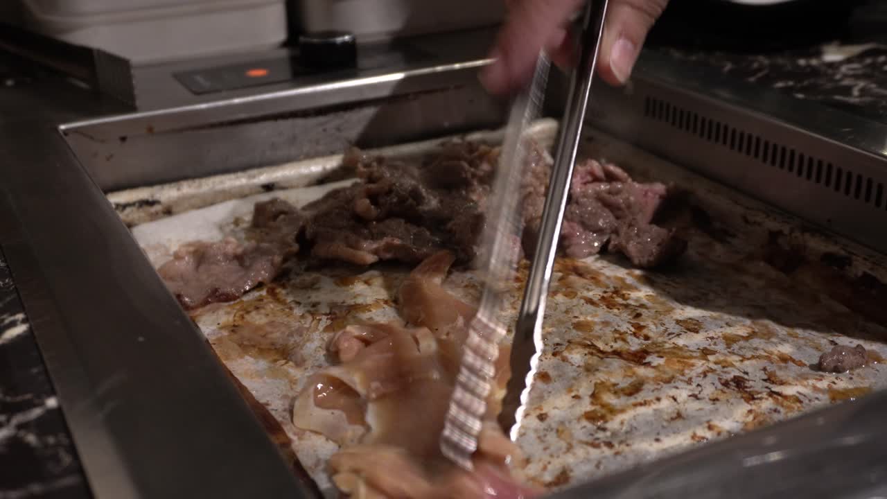 바베큐 한식 그릴에 닭고기 조각을 넣는 사람의 클로즈업 보기