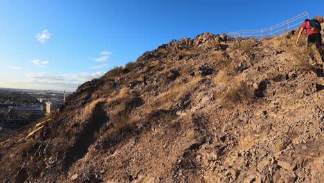 an unidentified hiker journeys up a mountain in the arizona state university to get a view of the city of tempe, arizona