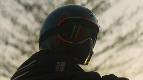 close-up of a person wearing a vintage motorcycle helmet and goggles