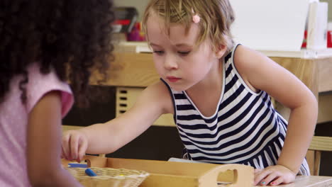 Pupils-At-Tables-Drawing-With-Crayons-In-Montessori-School-Class