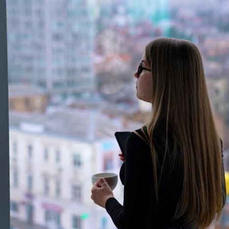 beautiful woman wearing eyeglasses using cellphone and drinking coffee