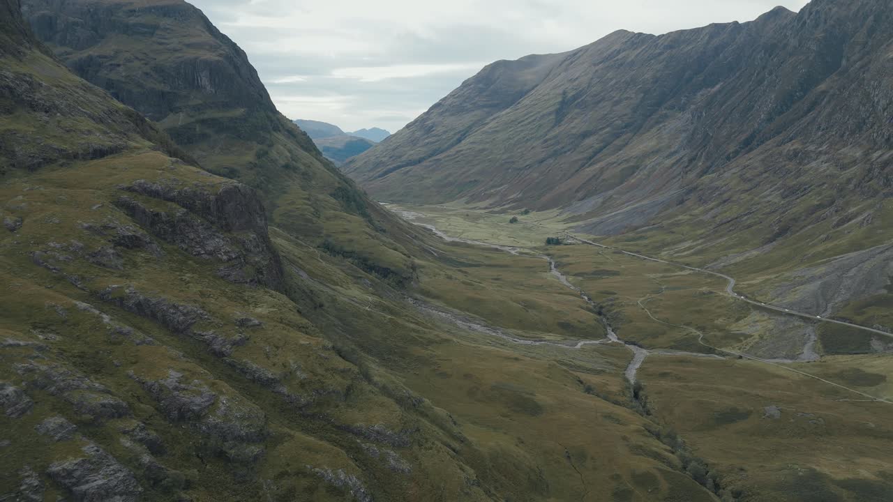Aerial left circle of the Three Sisters, Glencoe, Scotland, with sweeping views of rugged highland mountains and low rods in the valley