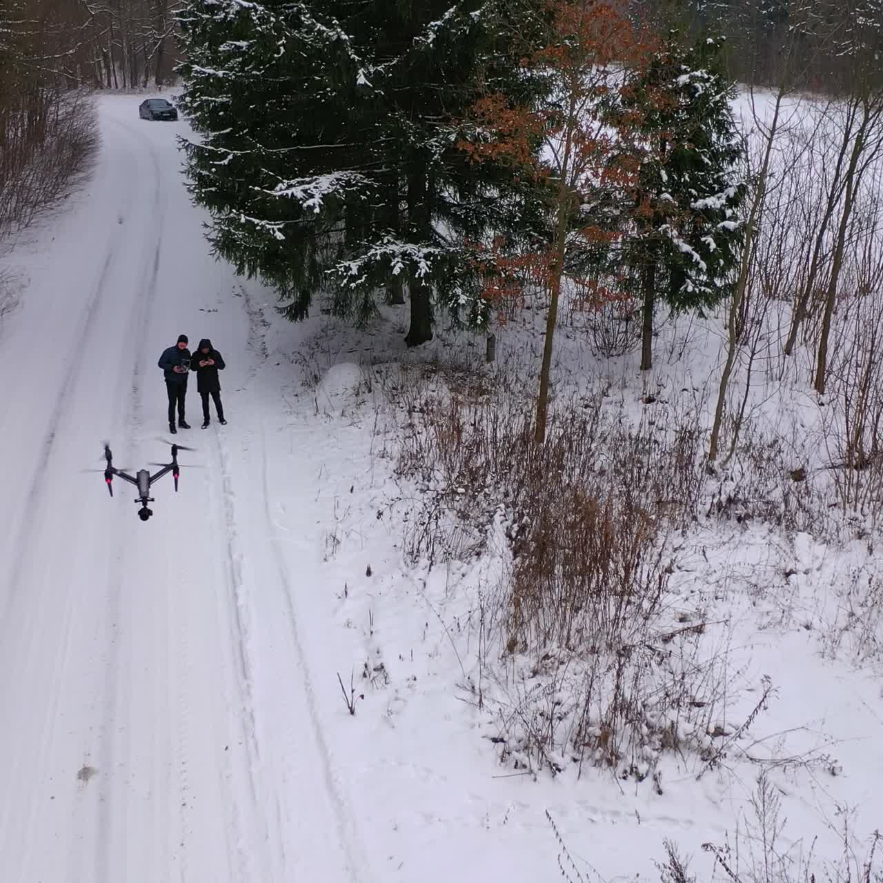 People launching drone in winter landscape. Beautiful nature covered with snow. Snowy weather in woodland. Drone view