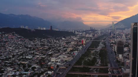 aerial view of river cutting through city of monterrey, mexico with vibrant sunset background