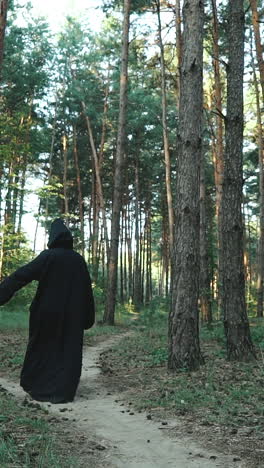 halloween horror man with black cape walking in forest. vertical video