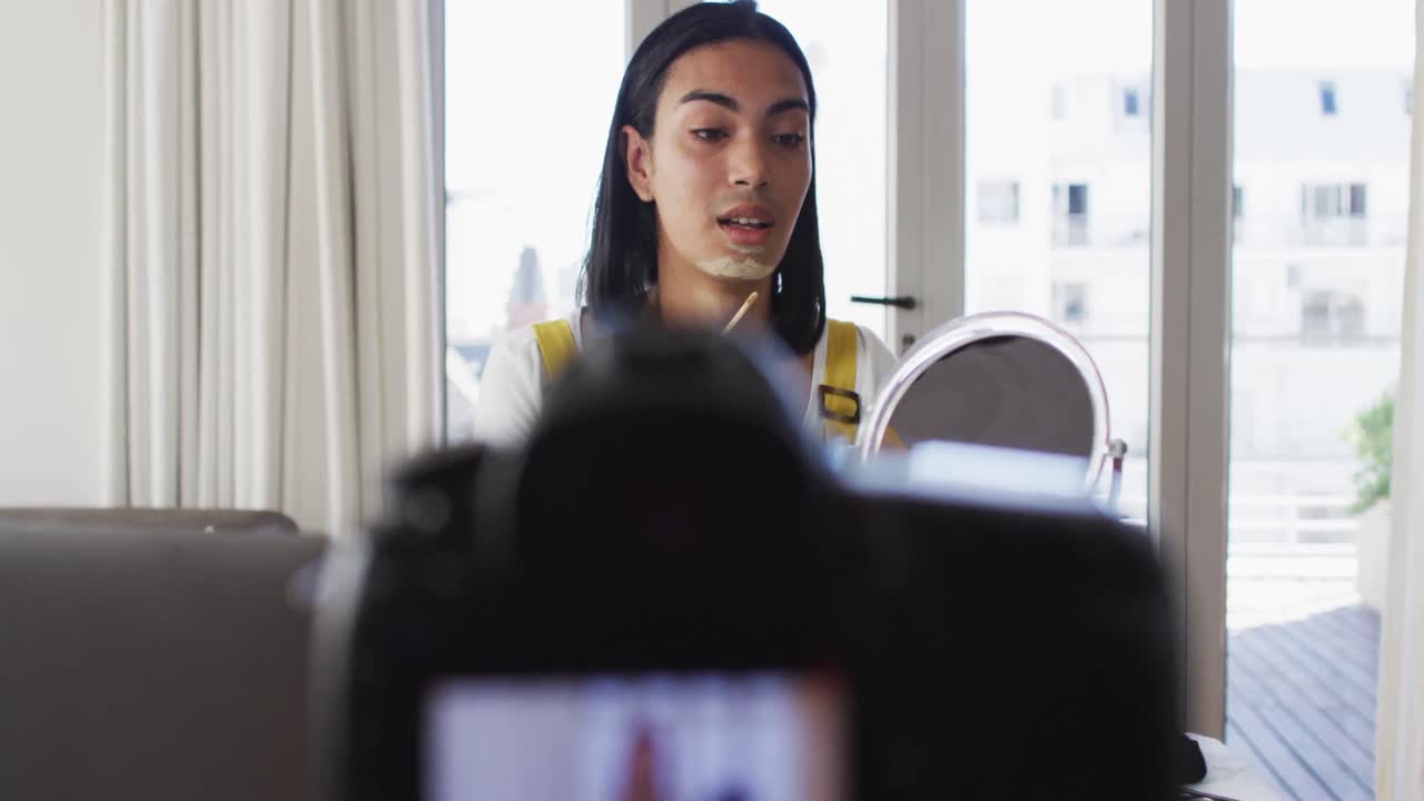 vlogger de género fluido de raza mixta grabando un vlog de maquillaje en casa