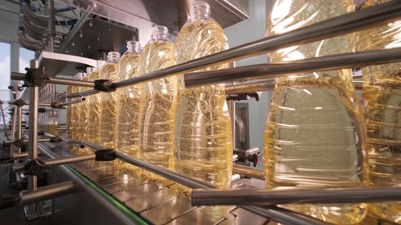 Sonnenblumenöl in der Flasche bewegt sich auf der Produktionslinie. Abfüllanlage für Sonnenblumenöl in Flaschen. Pflanzenölproduktionsanlage. Hochtechnologie. Industrieller Hintergrund.