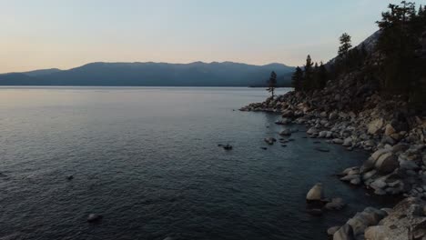 disparo de drones volando por tres personas sentadas en las enormes y suaves rocas en la orilla este del lago tahoe durante la puesta de sol