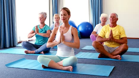 trainer assisting senior citizens in practicing yoga