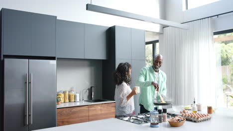 Feliz-Pareja-Birracial-Cocinando-Tortilla-En-Sartén-En-La-Cocina,-Cámara-Lenta