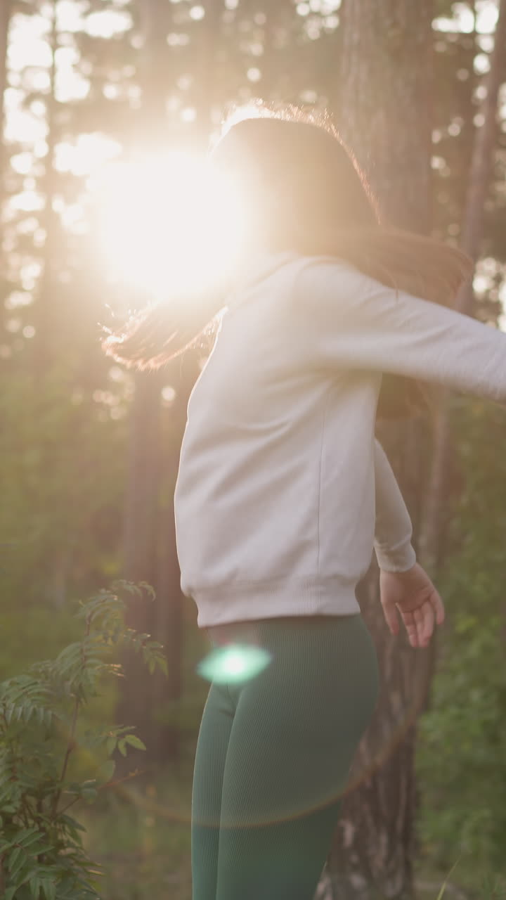 mujer realiza ejercicios de salto en el lugar en el bosque. dama hace actividad cardio para calentarse antes de correr al atardecer. rutina de fitness en la naturaleza para dar forma al cuerpo