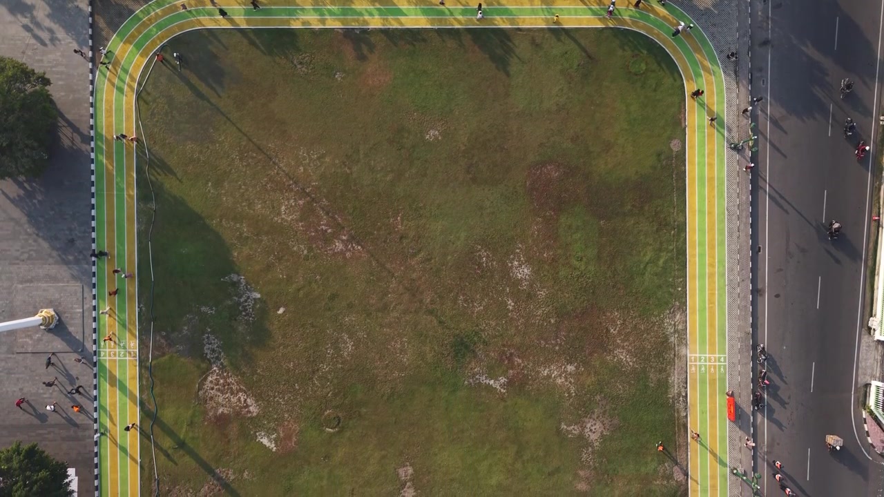Nedoverrettet 4K droneopptak viser løpere som bruker joggeløypen på Paseban Field, Bantul, Indonesia