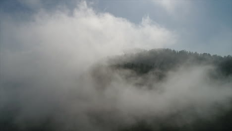 static drone shot of fog rolling over a mountain top