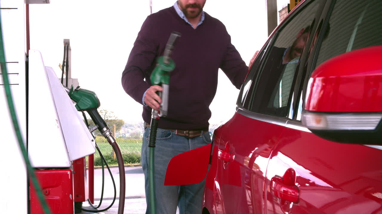 hombre llenando de combustible un coche en una gasolinera