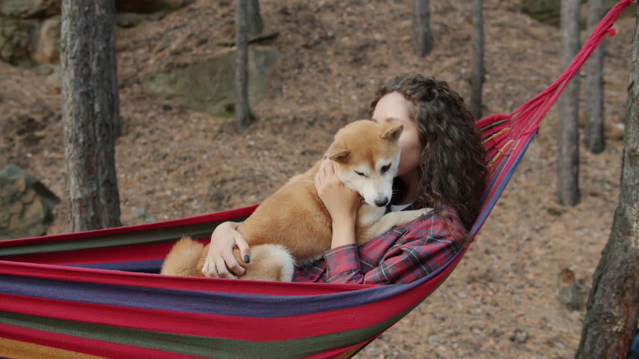 Woman relaxing in hammock with puppy