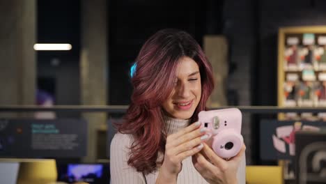 Positive Smiling Girl Chooses Digital Camera in Digital Store. Positive smiling girl chooses digital camera in digital store. A selection of quality digital goods in a specialized store