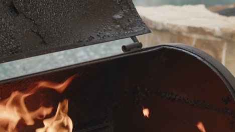 slow motion flames rising out of backyard bbq grill tilts down to charcoal