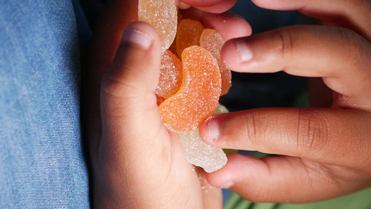 Hands holding a pile of colorful sugared gummy candies