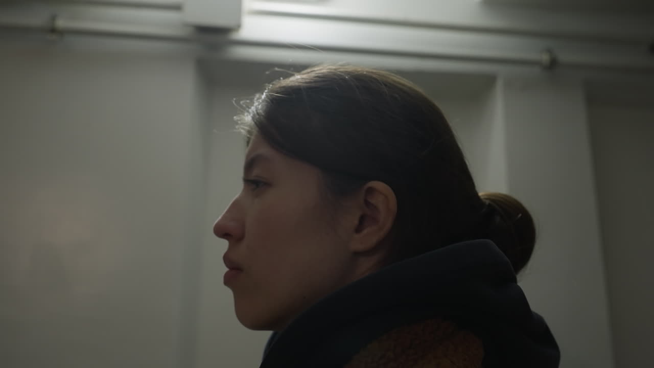 갈색 코트를 입은 불안한 소녀의 클로즈업, 우울한 표정으로 쳐다보고, 그림은 그녀가 깊은 생각에 빠져있는 것처럼 그녀의 프로필을 포착하여 슬의 느낌을 전달합니다.