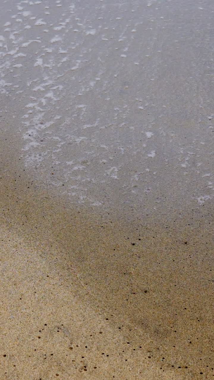 Close up of sea foam on a sandy beach
