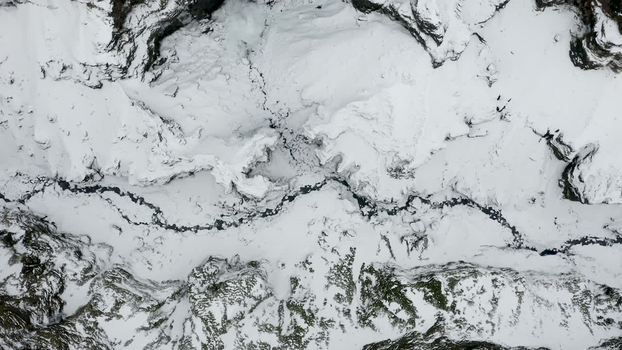 Aerial sideways looking straight down into a deep canyon, frozen wintery arctic landscape in Iceland.