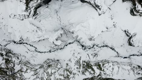 aerial sideways looking straight down into a deep canyon, frozen wintery arctic landscape in iceland.