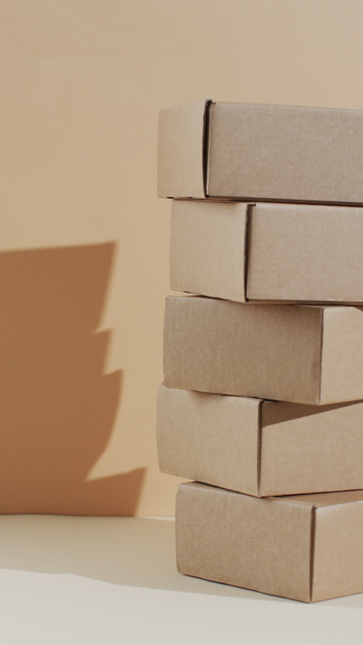 Vertical video of stacked cardboard boxes with copy space over brown background