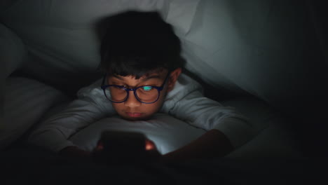 Close-Up-Of-Young-Boy-In-Bedroom-At-Home-Using-Mobile-Phone-To-Text-Message-Under-Covers-Or-Duvet-At-Night-6