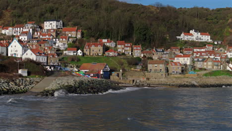 Low-Establishing-Shot-of-Runswick-Bay-Village-over-Sea-Yorkshire-UK