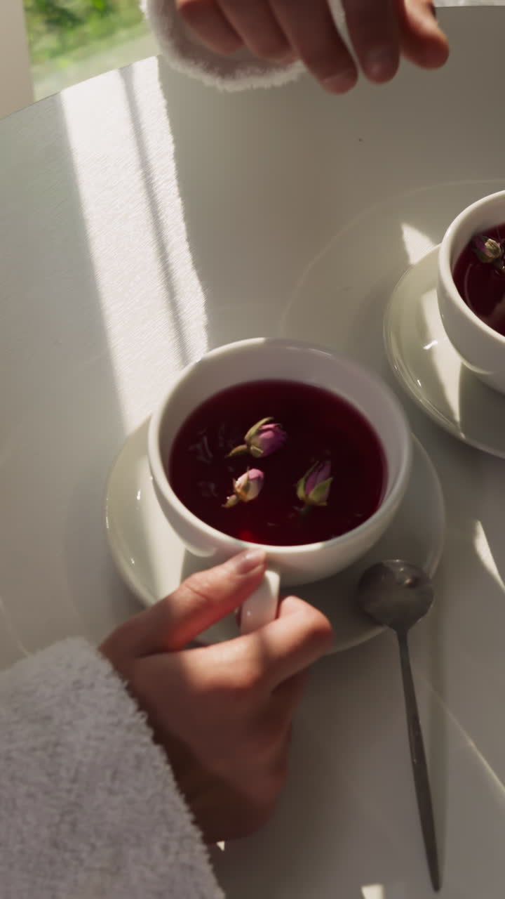 el hombre agrega brotes de rosas al té de la mujer en la mesa de primer plano. el marido cuidadoso prepara un desayuno romántico para la esposa en casa por la mañana. atmosfera de cita doméstica