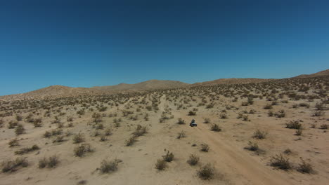 Montando-Un-Vehículo-De-Cuatro-Ruedas-En-El-Accidentado-Paisaje-Del-Desierto-De-Mojave-Visto-Desde-Un-Dron-En-Primera-Persona