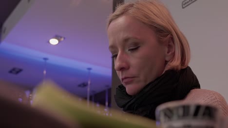 mujer rubia hambrienta caucásica leyendo el menú en el restaurante