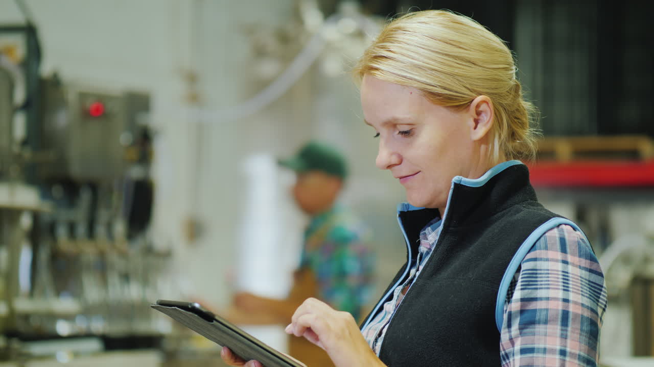 Jonge vrouw werkt met een tablet aan een productielijn in een drankenfabriek
