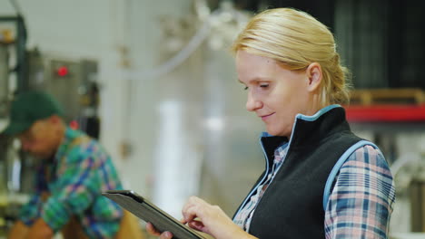 young woman works with tablet  on drinks factory production line