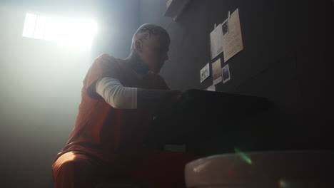 nervous inmate writing letter and throwing away paper in prison cell