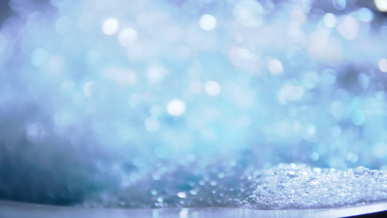 회전 슬로우 모션 및 파란색 복사 공간 배경이 있는 예술적 흐림 거품 및 점