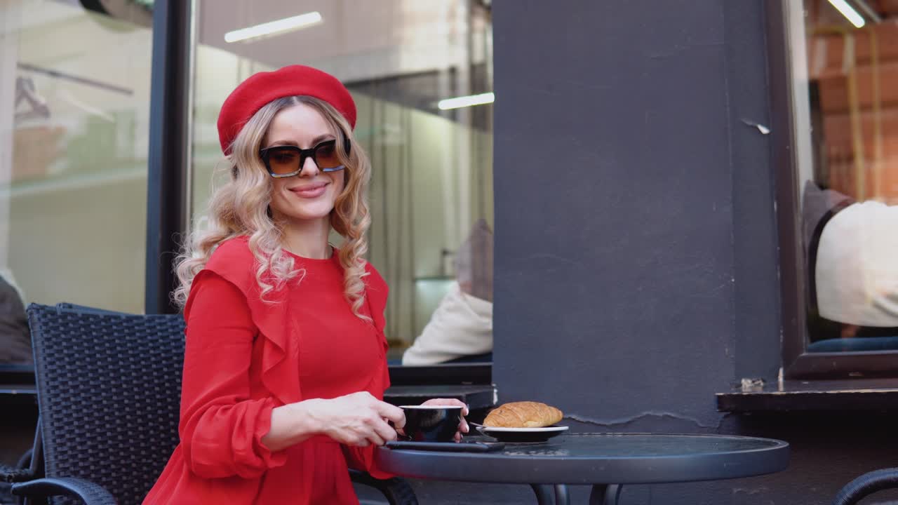 Aesthetics of red and black colors. French breakfast. Young romantic woman drinking coffee with a croissant