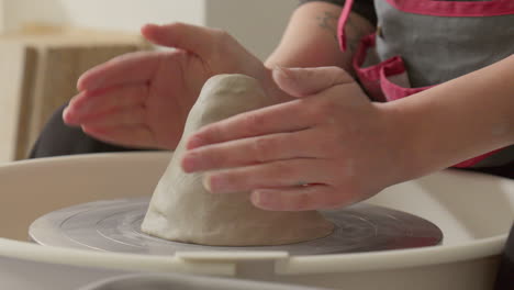 pottery artist with hands securing a piece of clay on the throwing wheel preparing for work with it