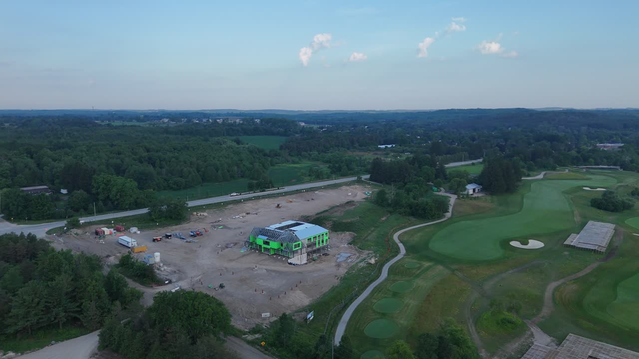 An aerial drone view of the new, modern clubhouse at TPC Toronto (Osprey Valley) under construction, set against the pristine green fairways of the golf course