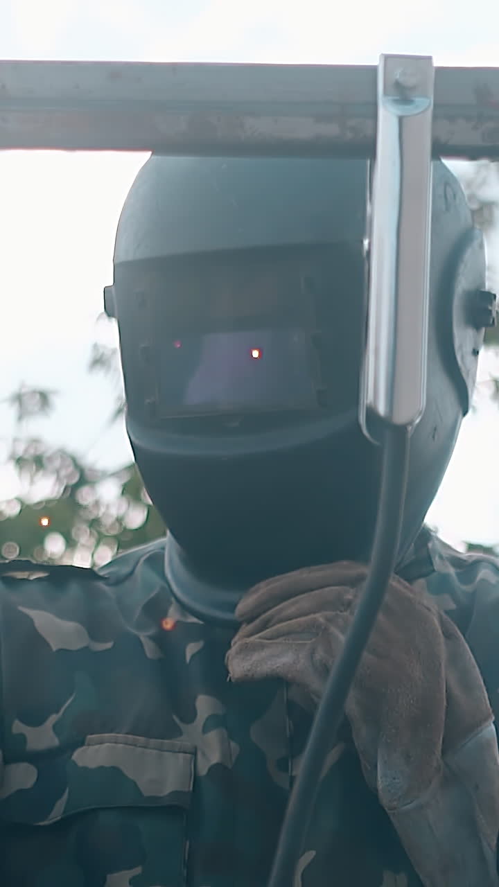 slow motion craftsman in workwear welds upper rail of metal fence with modern instrument on daytime