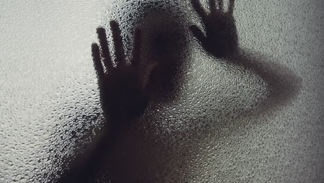 a female silhouette behind the frosted glass moves slowly
