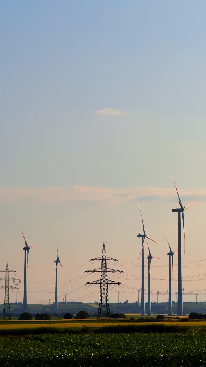 Renewable energy from wind. Wind turbines stand tall against a clear sky, harnessing wind energy in a green field at sunset
