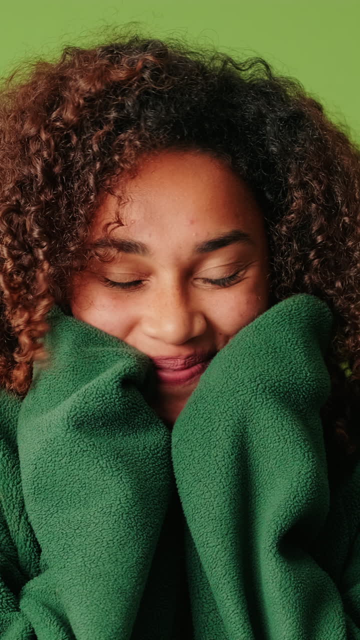 Giovane donna sorridente con capelli ricci che posa in modo giocoso