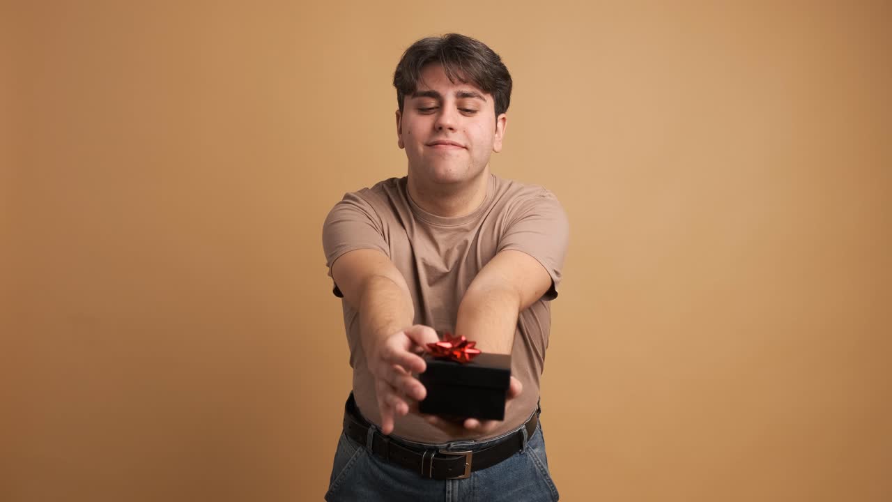 Happy man giving present and looking at camera