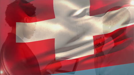 animation of flag of switzerland waving over diverse businesswomen discussing with tablet