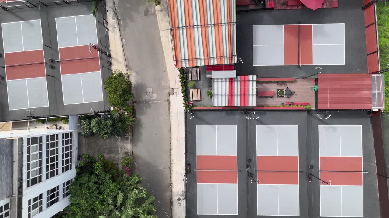 pickleball canchas vista aérea en un día soleado. pickleball en un deporte popular y actividad social. la cámara se mueve de derecha a izquierda con una piscina en la azotea y la carretera.