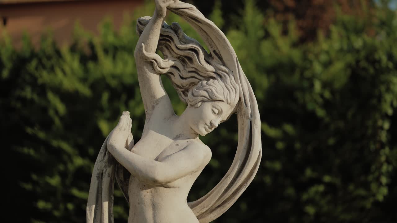 Graceful stone statue of a woman with flowing hair captured in warm natural lightilluminated by warm natural light. The sculpture shows artistic craftsmanship