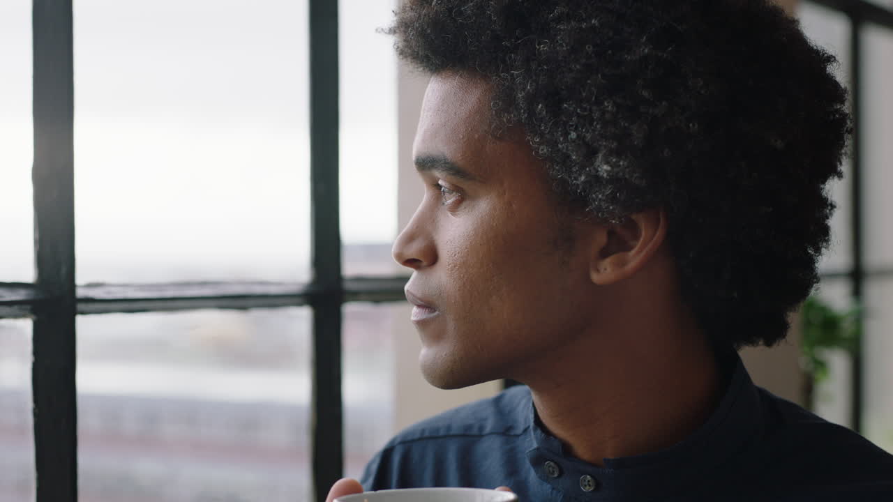 portrait young businessman drinking coffee at home entrepreneur enjoying calm relaxed morning looking out window thinking contemplative trendy afro hairstyle