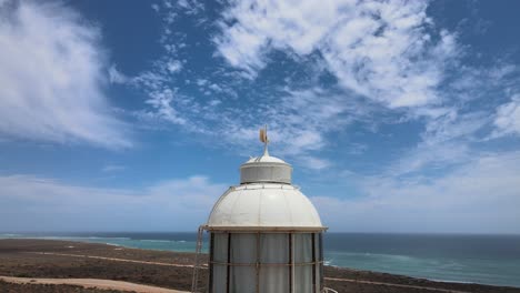 aerial - vlamingh head lighthouse in pacific ocean, western australia, close to town and blue sky and clouds, orbit circle shot